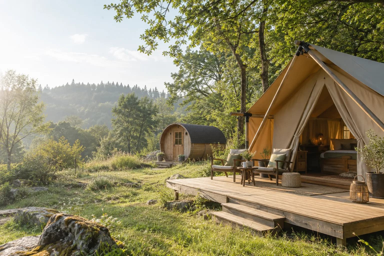 Safarizelt auf einer Holzterrasse und Schlaffass in einer Waldlichtung